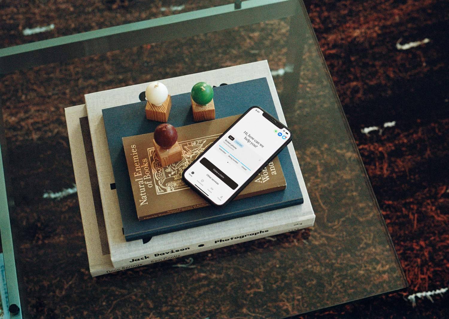 Phone on books on a glass table.